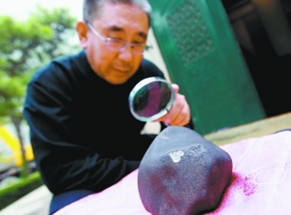 昨天,北京天文馆陨石专家张宝林正在对神秘陨石进行研究.
