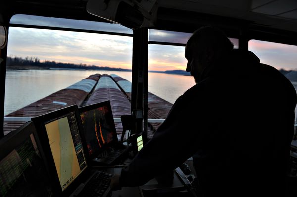 A pilot oversees navigation equipment while directing grain barges on the Missis